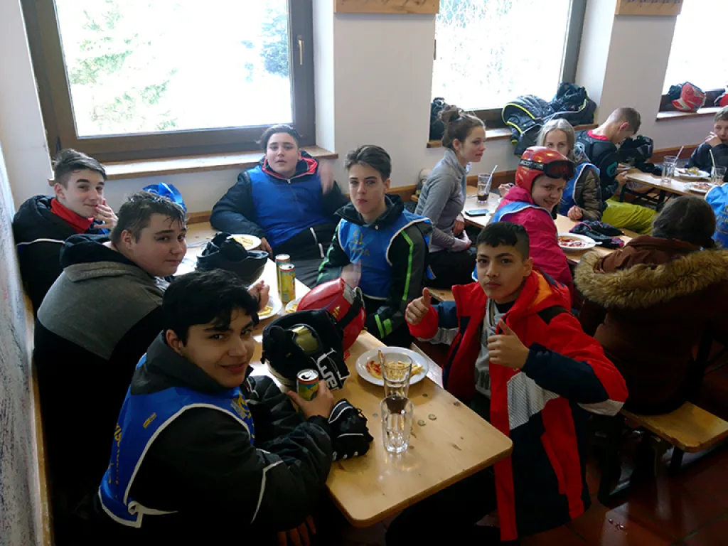Jugendliche sitzen beim Essen an einem Tisch der Skihütte.